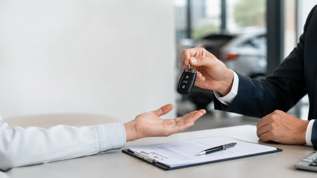 Autohändler übergibt Fahrzeugschlüssel nach Vertragsunterschrift beim Autoankauf